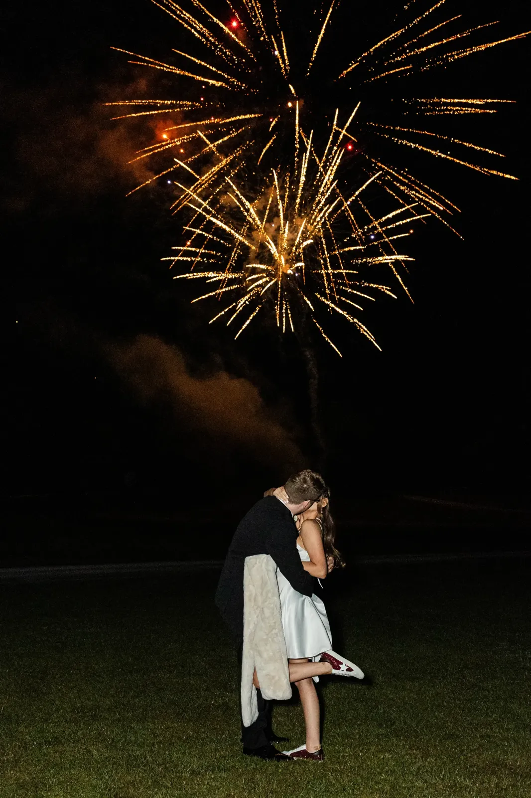 Couple kissing under fireworks at wedding reception