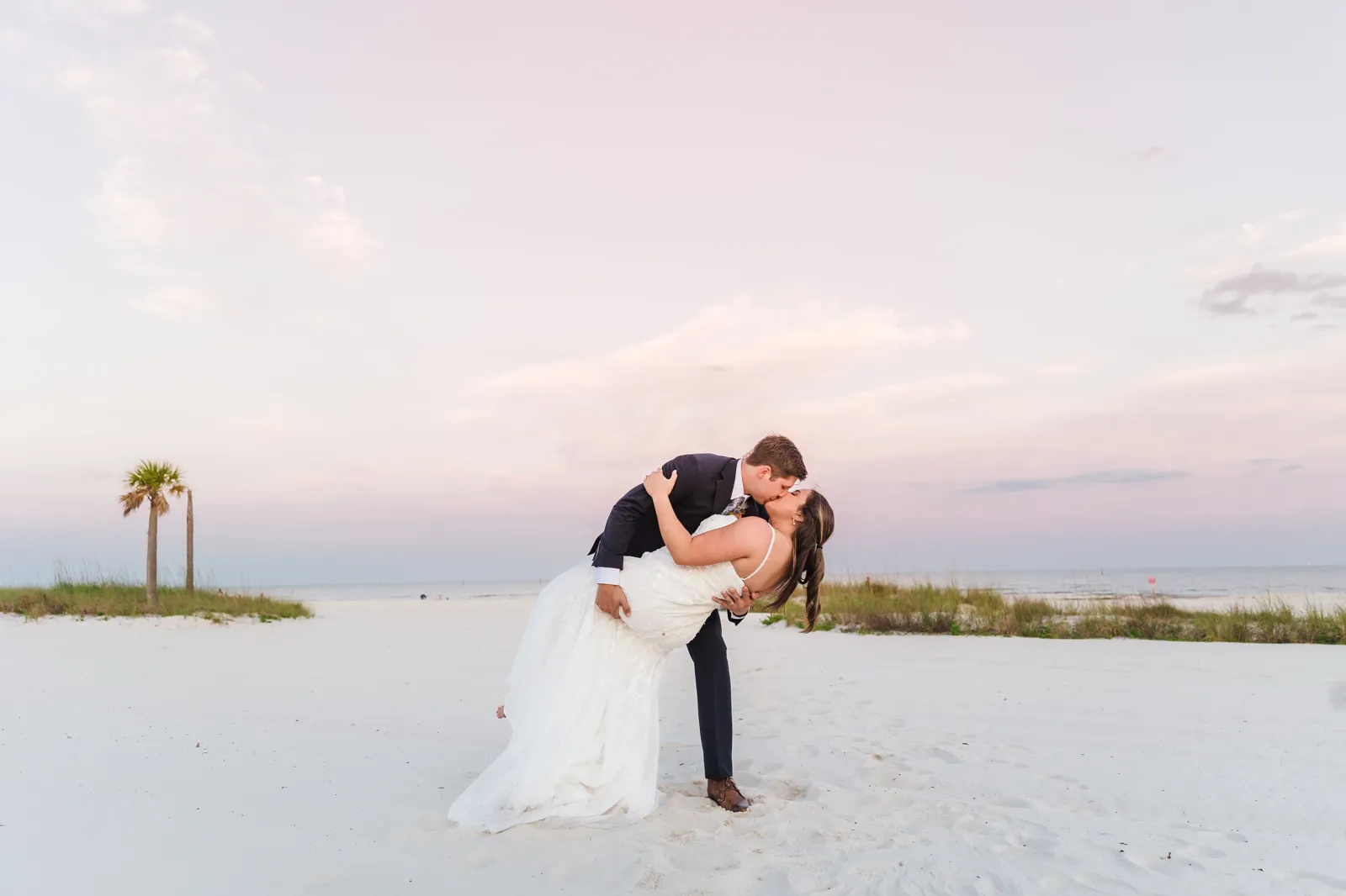 Beach dip kiss at sunset with palm trees
